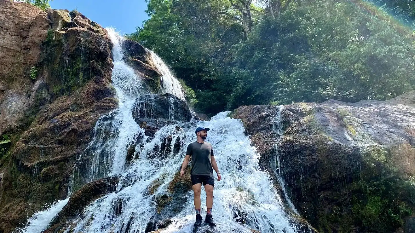 Un homme debout devant une chute d’eau