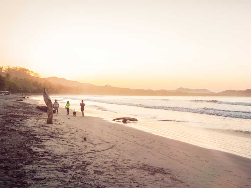 Un groupe de personnes debout au sommet d’une plage de sable.