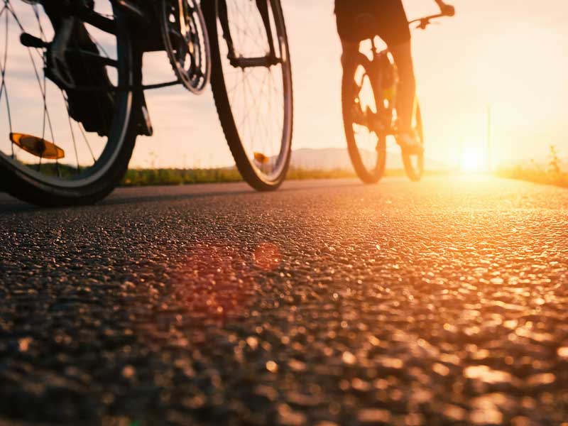 Une personne faisant du vélo dans une rue au coucher du soleil.