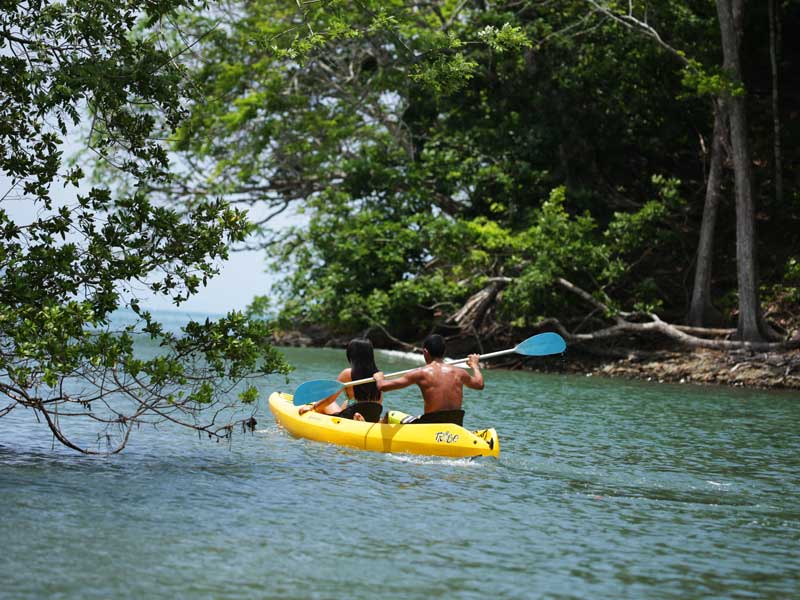 Un homme pagaie sur un kayak dans l’eau.