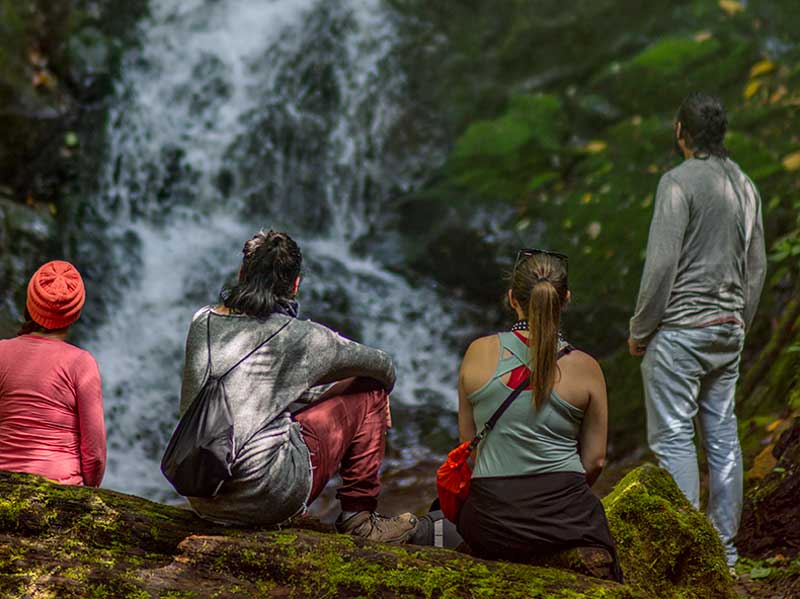 Un groupe de personnes assises sur un rocher regardant une cascade.