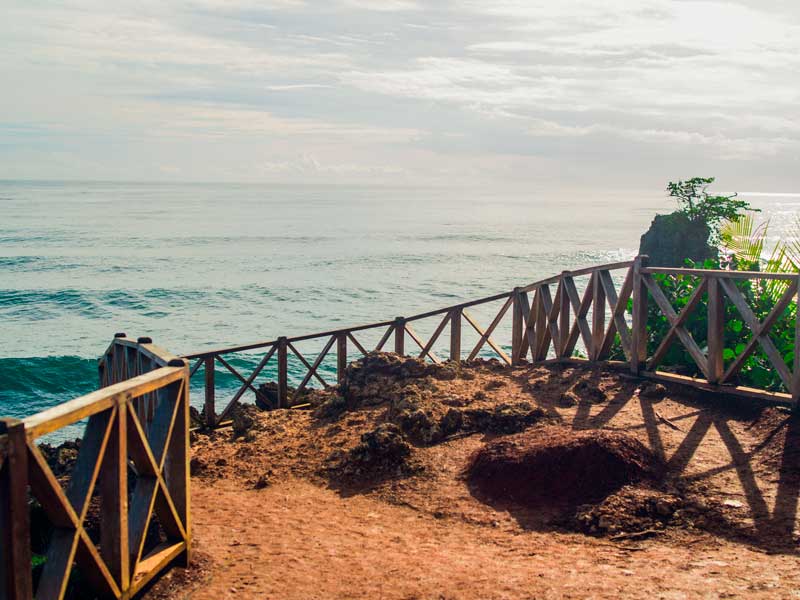 Une passerelle en bois menant à l’océan par temps nuageux.