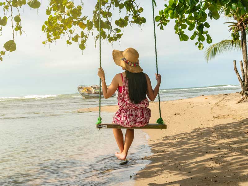Une femme assise sur une balançoire à la plage.
