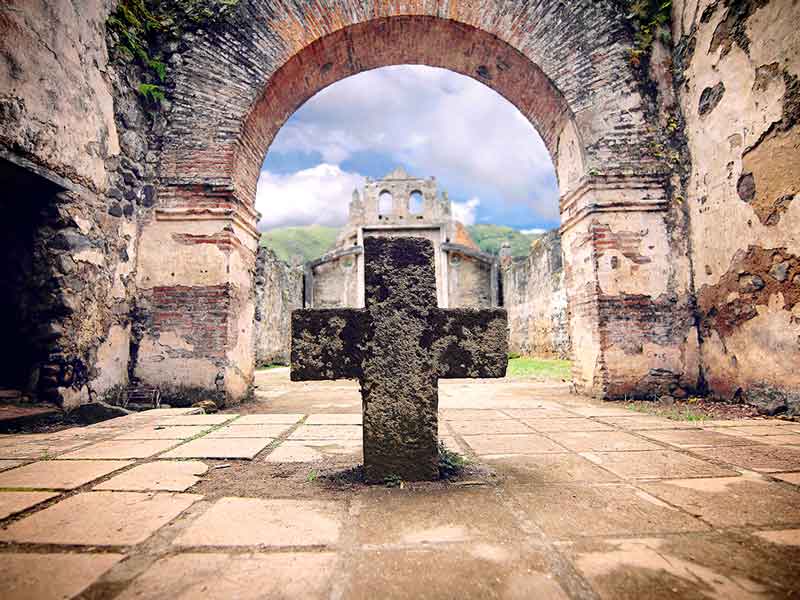 Une croix de pierre au milieu d’une cour.