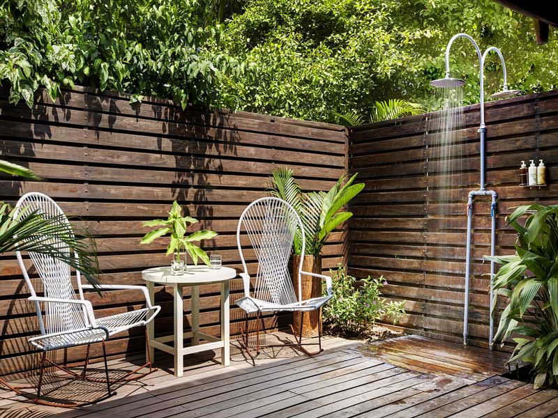 Une terrasse en bois avec deux chaises et une table.