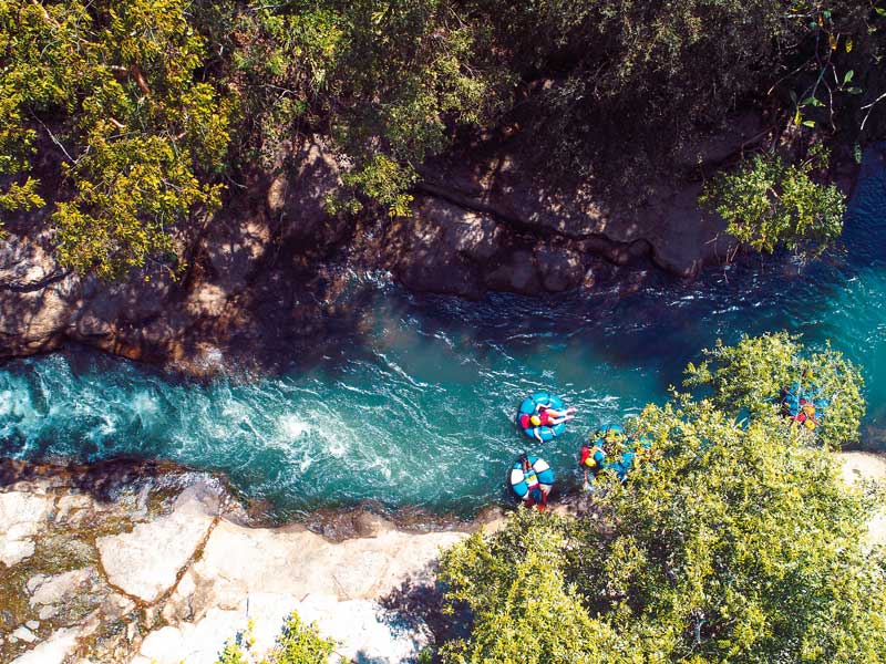 Un groupe de personnes dans des radeaux pagayant sur une rivière.