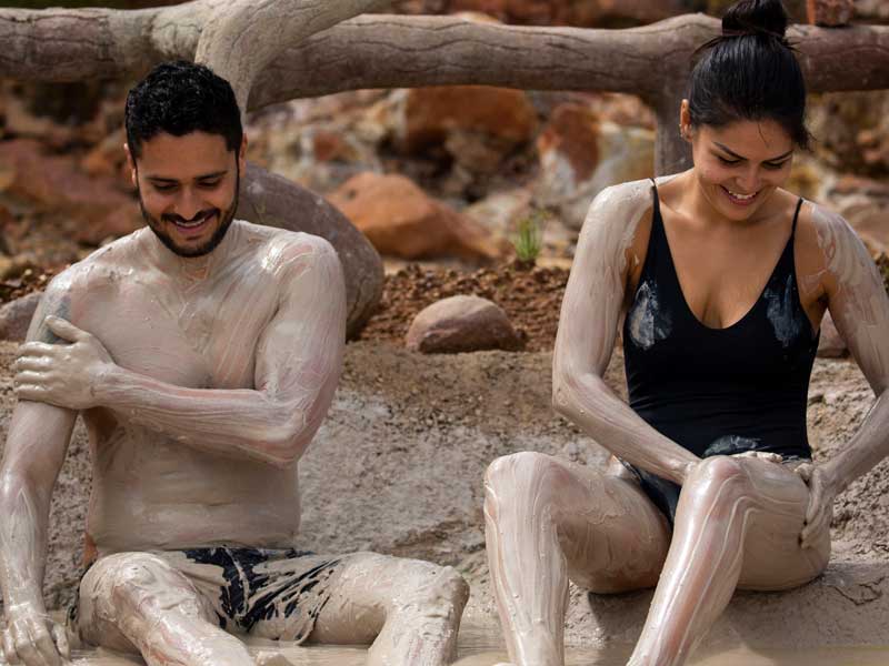 Un homme et une femme couverts de boue sont assis sur le sol.