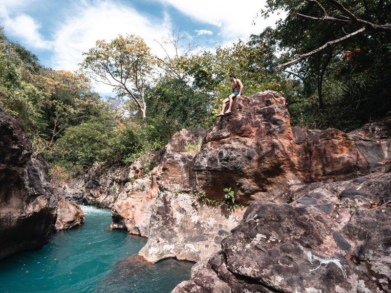 Une personne assise sur un rocher au-dessus d’une rivière.