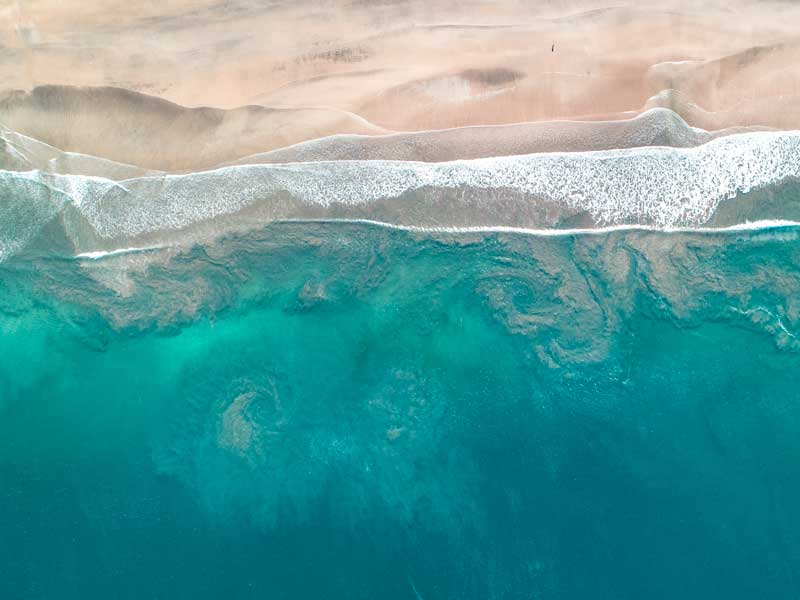 Une vue aérienne d’une plage de sable et de l’océan.