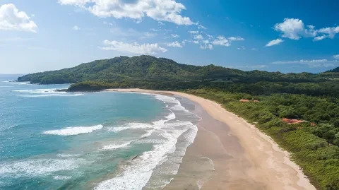 Vue aérienne d'une plage de sable le long Costa Rica Sa côte du Pacifique, bordée d'eaux turquoise et de collines verdoyantes.