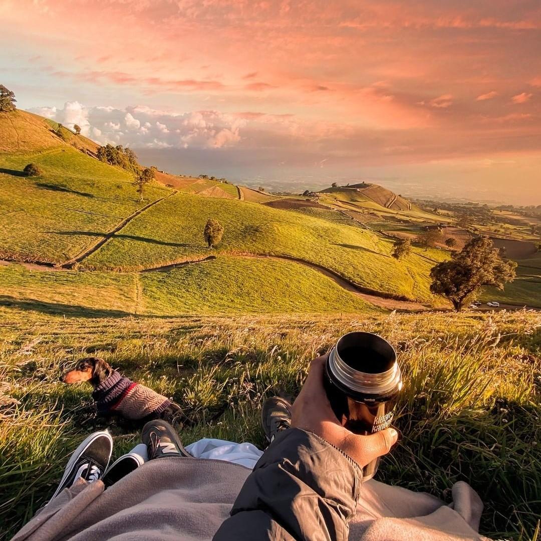 Un homme regardant un coucher de soleil sur une colline verdoyante