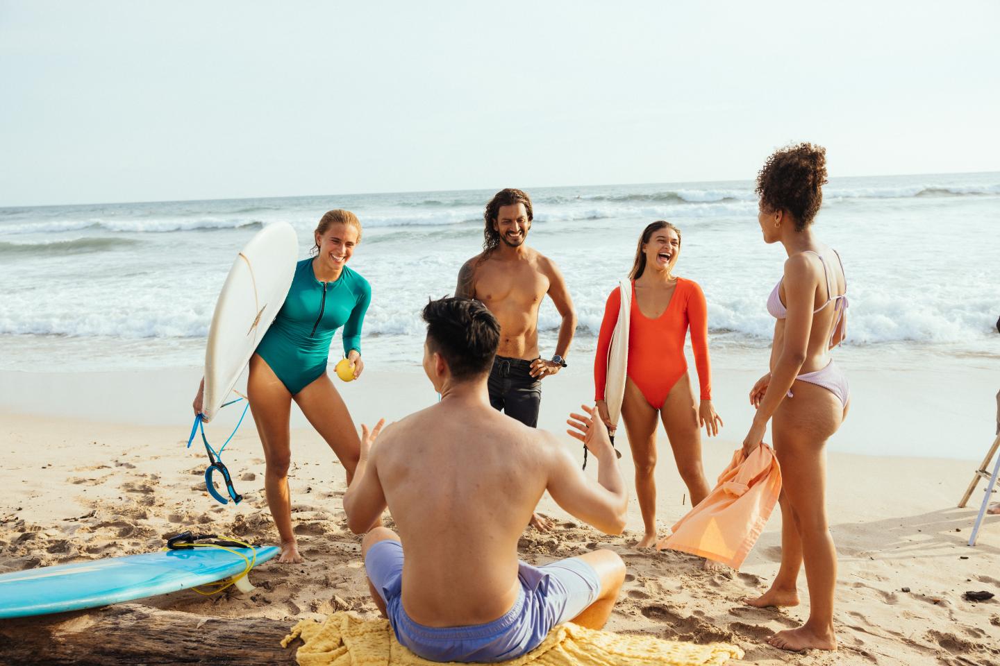 Des amis rient avec des planches de surf sur la plage Guiones