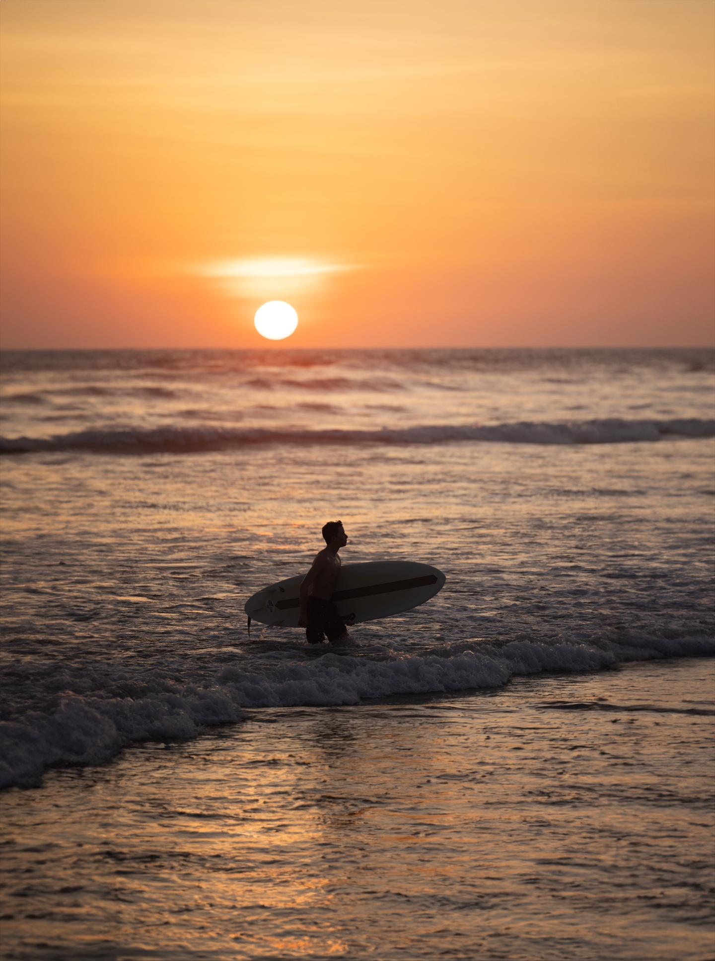 Homme surfant au lever du soleil dans l’océan Guiones
